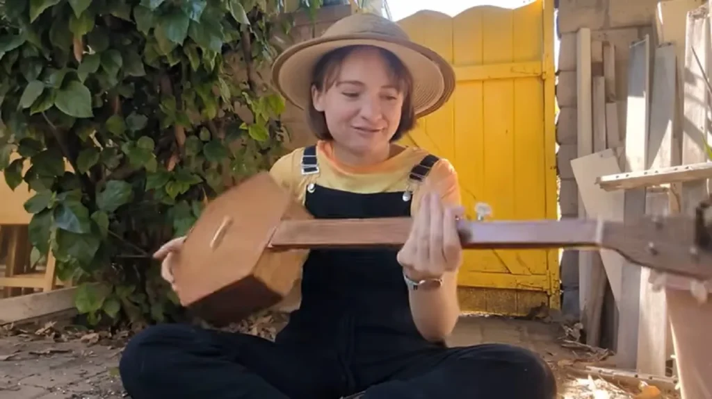 Phoebe’s music video, fretless banjo, charming chicken, Down in the River to Pray, authenticity, whimsical, homely vibe, heartfelt performance, simplicity, nostalgia.